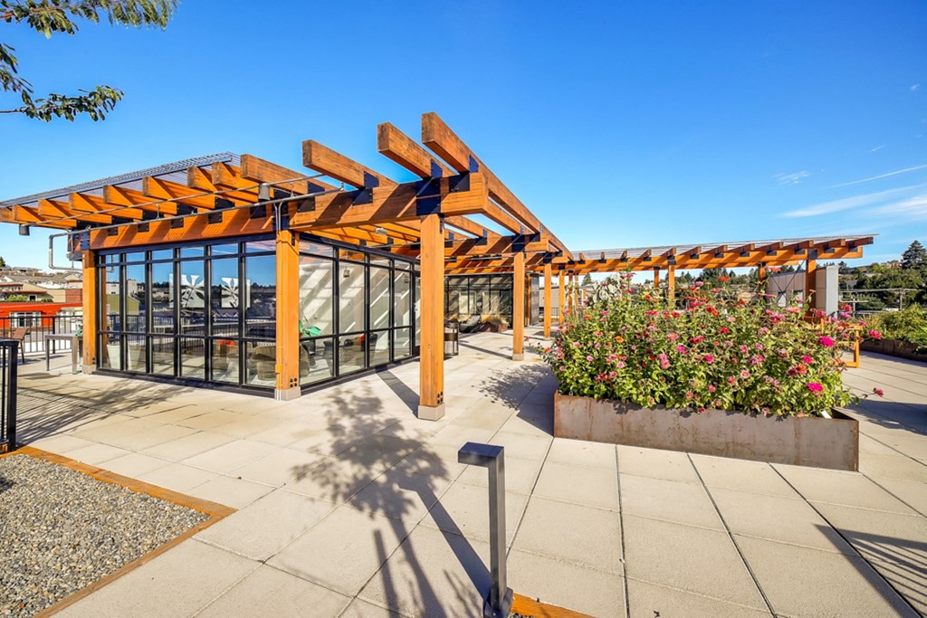 a covered patio with flowers and a glass building with a roof