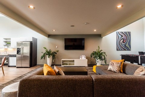 A modern living room with a brown couch and a television on the wall.