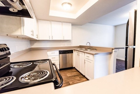 A modern kitchen with a stove top oven and white cabinets.