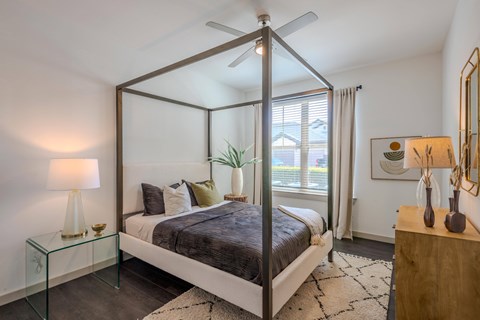 A bedroom with a bed in the center and a ceiling fan above it.