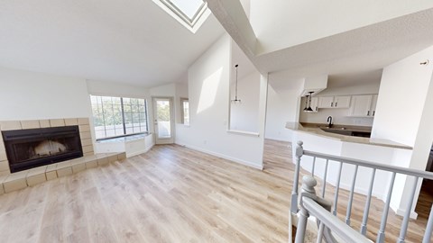 A spacious living room with a fireplace and a skylight.