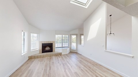A spacious room with a fireplace and skylight.