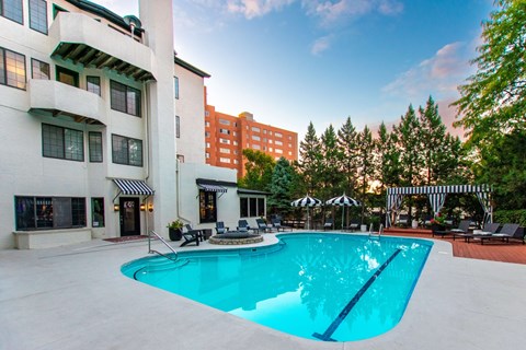 A large swimming pool in front of a white building with a black and white striped awning.