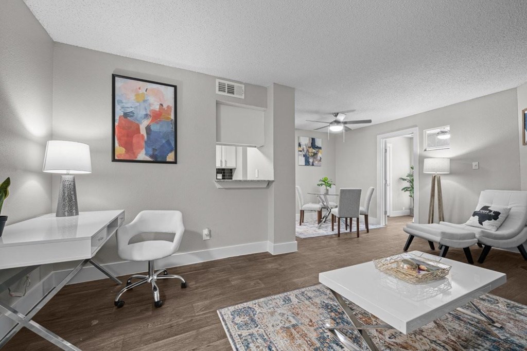 A living room with a white desk and white chairs.