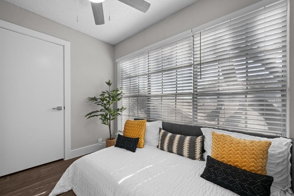 A bedroom with a bed, pillows, and a plant.