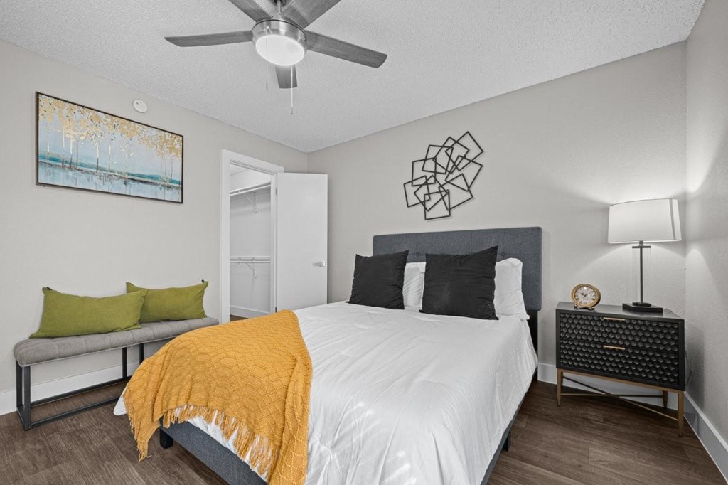 A bedroom with a bed, nightstand, and a painting on the wall.