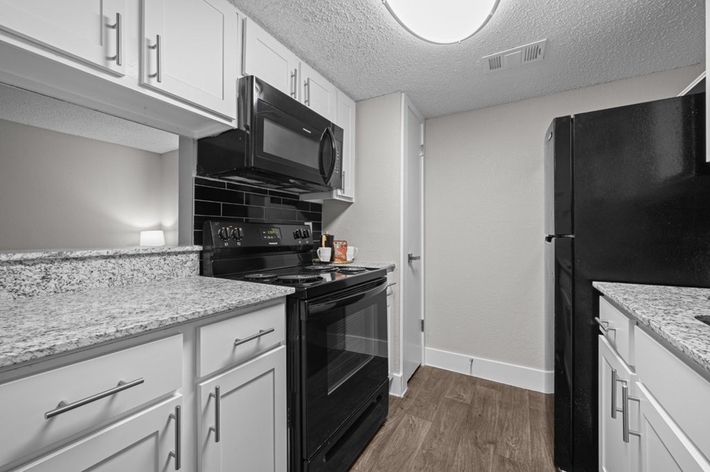 A kitchen with black appliances and white cabinets.