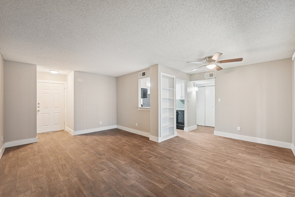 A room with a ceiling fan and wooden flooring.