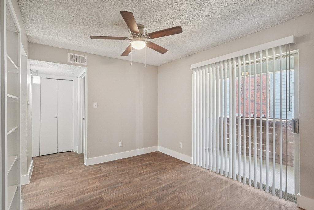 A room with a ceiling fan and a window with blinds.