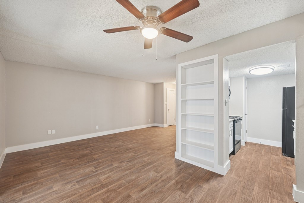 A room with a ceiling fan and wooden flooring.