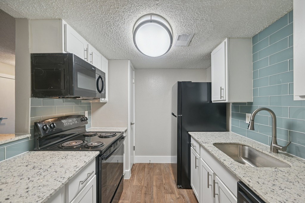 A kitchen with black appliances and white cabinets.