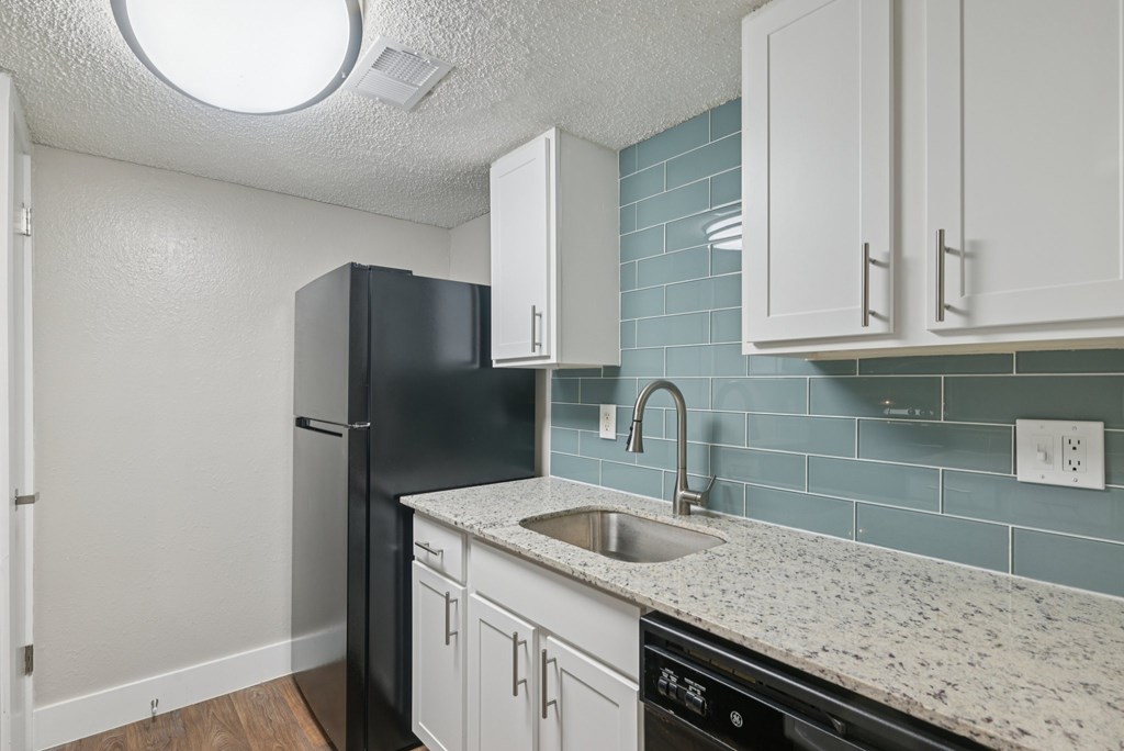 A kitchen with a black refrigerator and white cabinets.