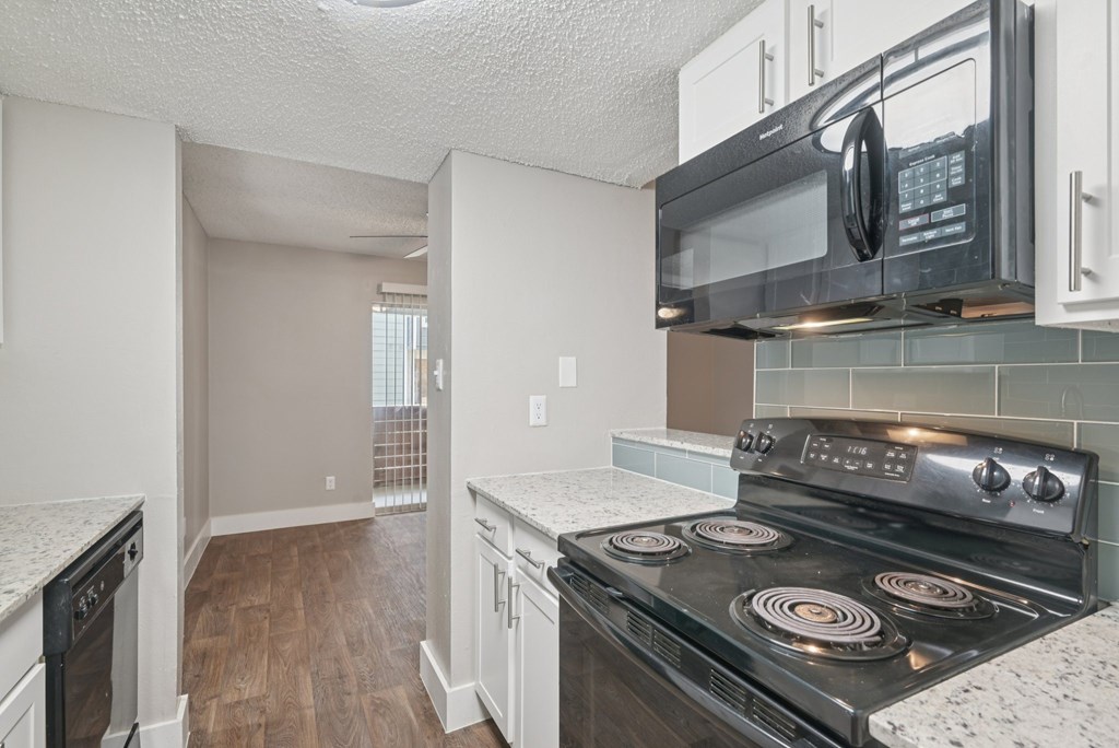 A kitchen with a black stove top oven and white cabinets.
