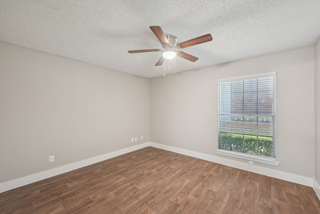 Empty room with a ceiling fan and a window.