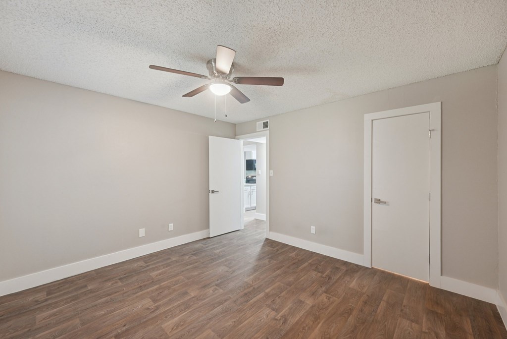 A room with a ceiling fan and wooden flooring.
