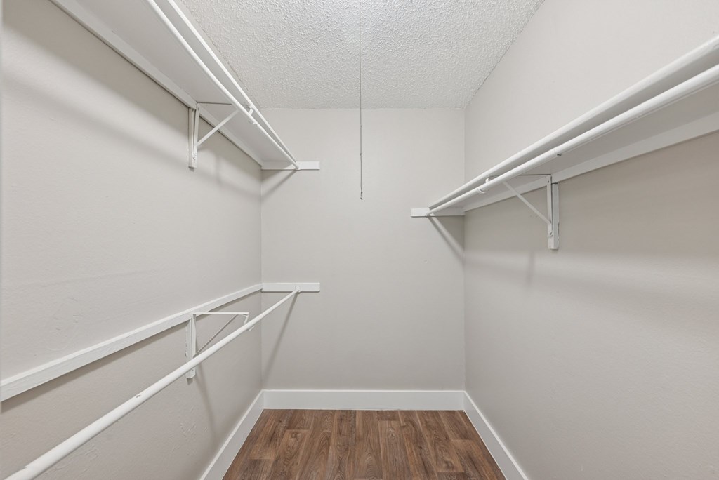 A white closet with shelves and a wooden floor.