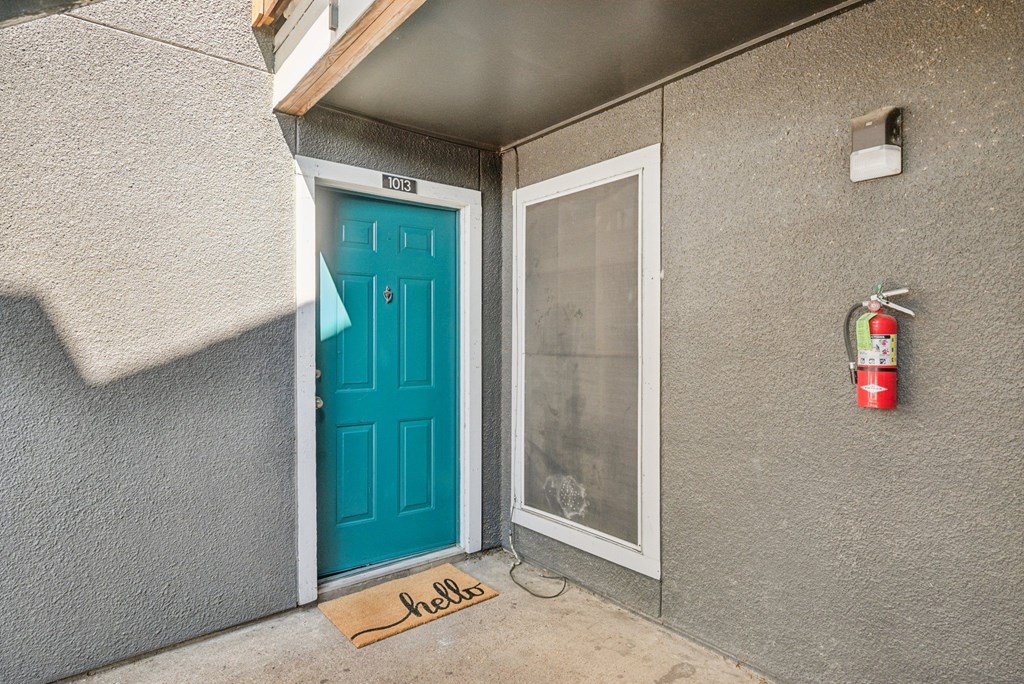 A blue door with a glass window and a mat that says
