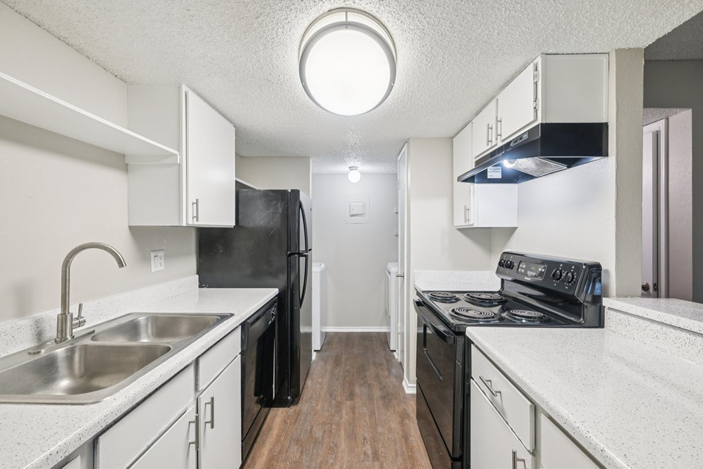 A kitchen with black appliances and white countertops.