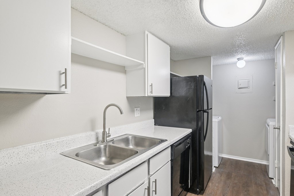A kitchen with a black fridge and white cabinets.