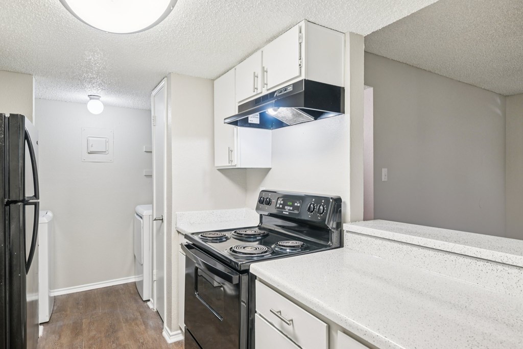 A kitchen with a black stove top oven and white cabinets.