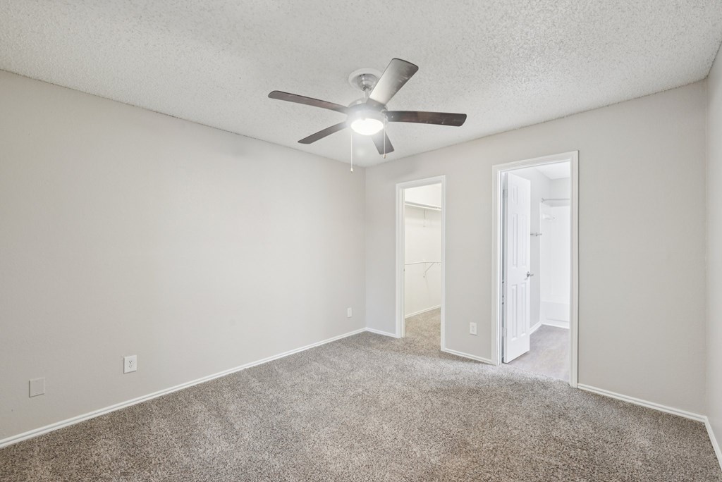 A room with a ceiling fan and carpeted floor.