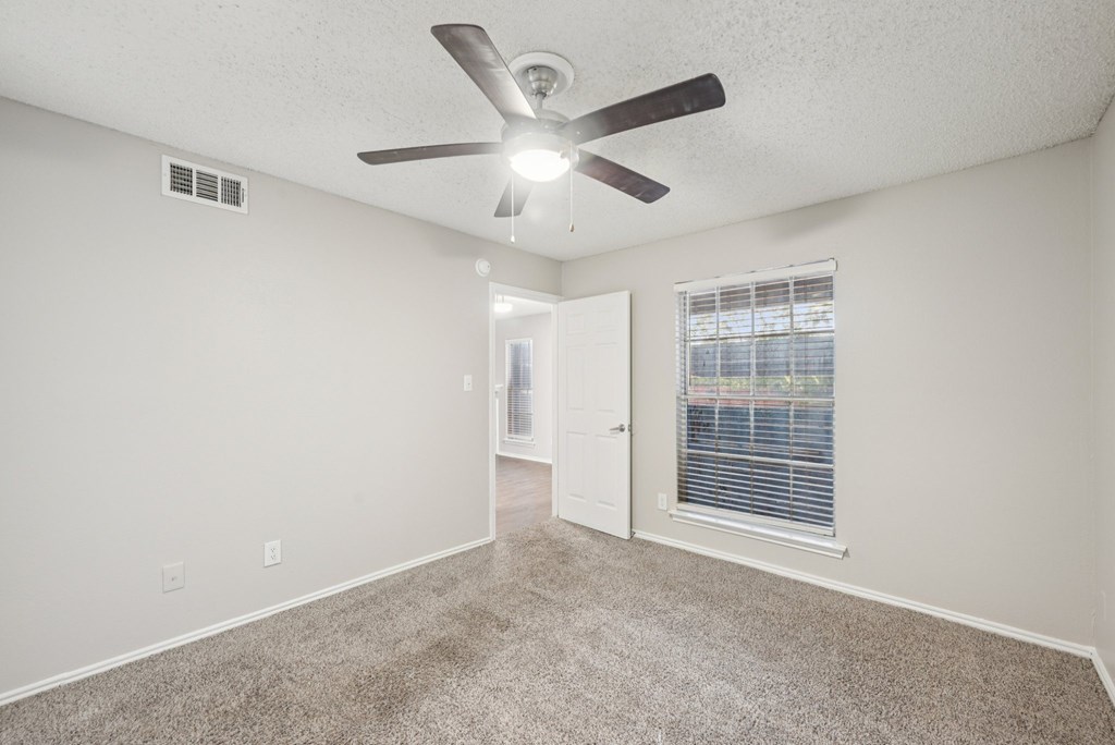 A room with a ceiling fan and carpeted floor.