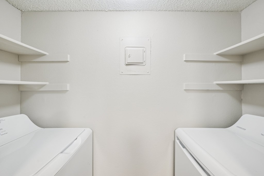 Two white washing machines in a laundry room.