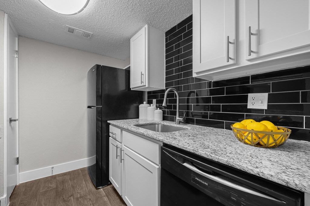 A kitchen with black appliances and white cabinets.