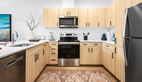 A kitchen with wooden cabinets and a black refrigerator.