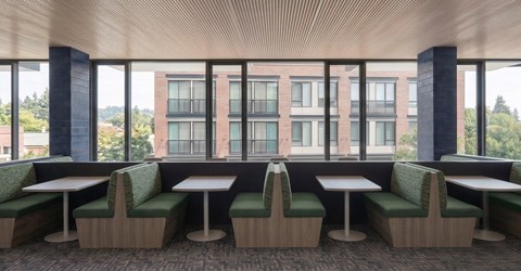 A restaurant with green chairs and tables with a view of a building outside.