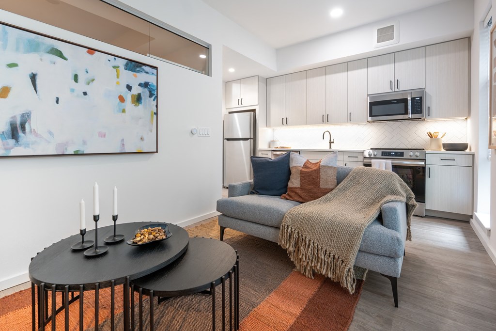 A modern kitchen with a blue couch and a painting on the wall.
