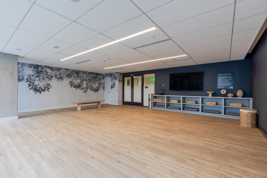 A room with wooden floors and a wall with a black and white floral wallpaper.