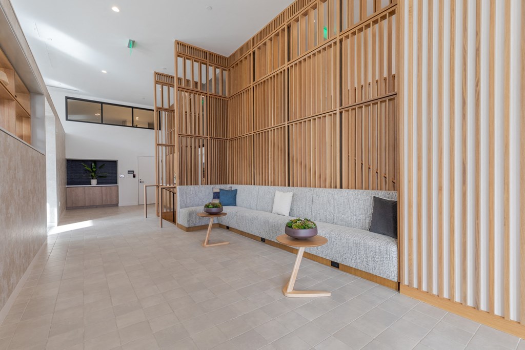 A modern living room with a grey sofa and a wooden wall panel.