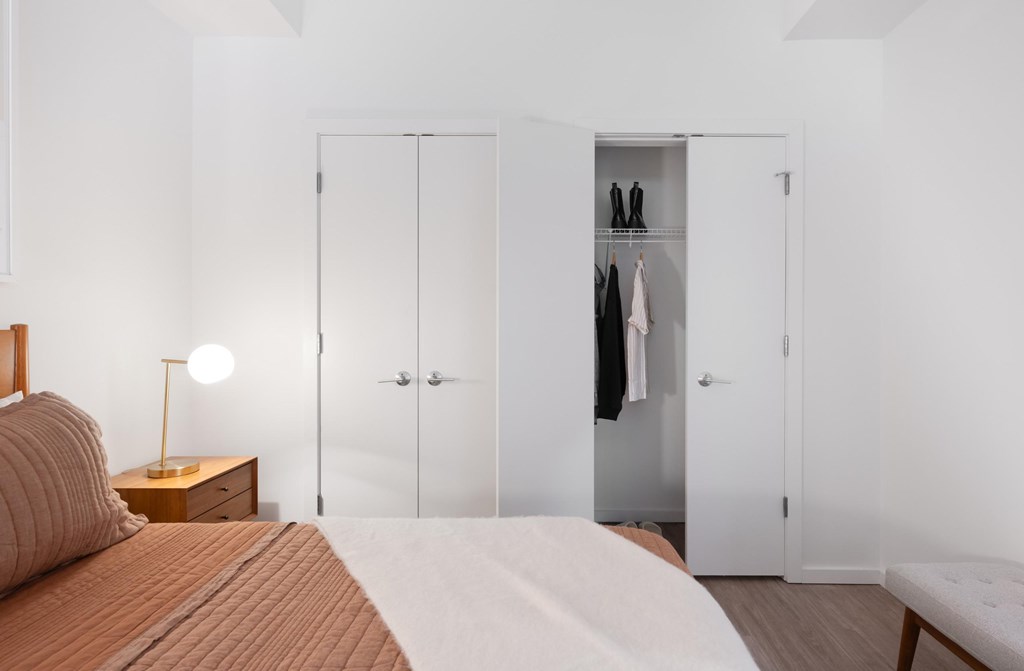 A bedroom with a bed, nightstand, and wardrobe.