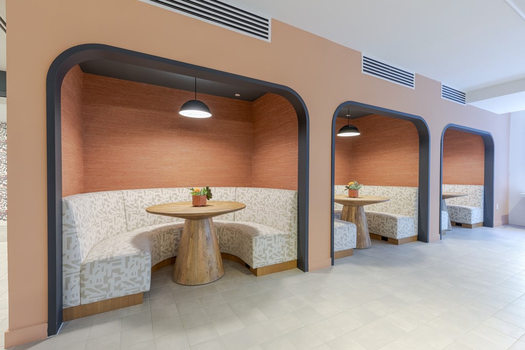 A modern dining area with a round wooden table and white patterned chairs.