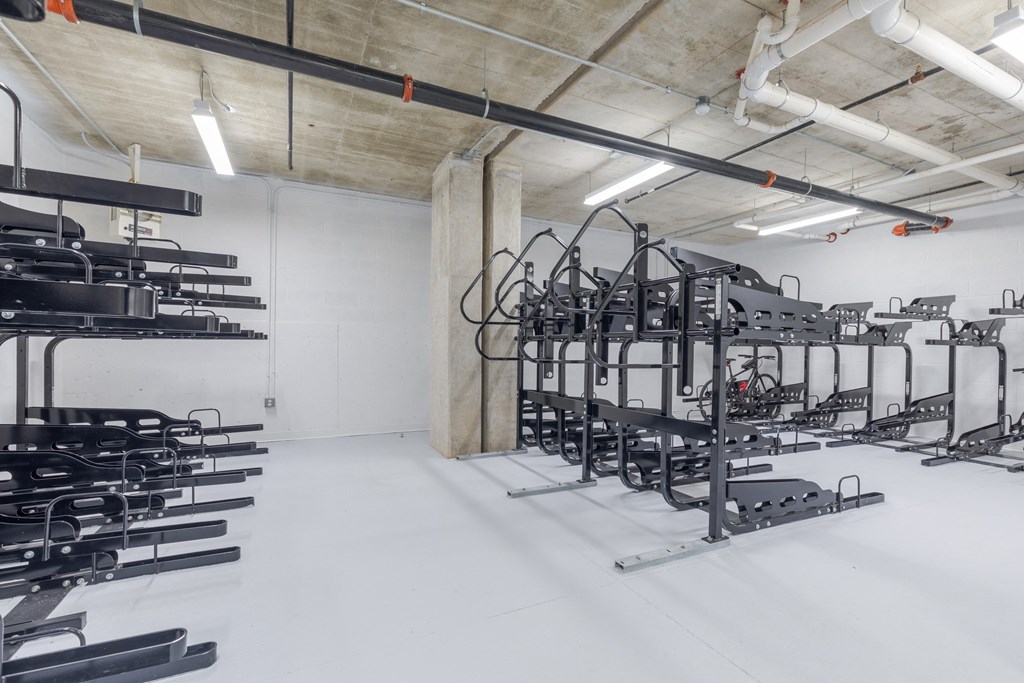 A gym with a white floor and white walls has a variety of exercise equipment.