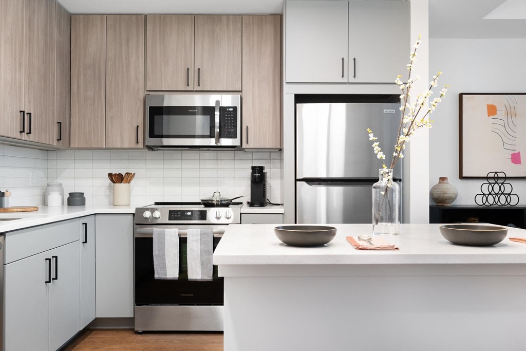 A modern kitchen with a stove, refrigerator, and cabinets.