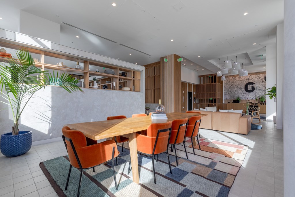 A dining room with a wooden table and orange chairs.