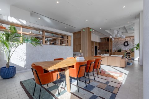 A dining room with a wooden table and orange chairs.
