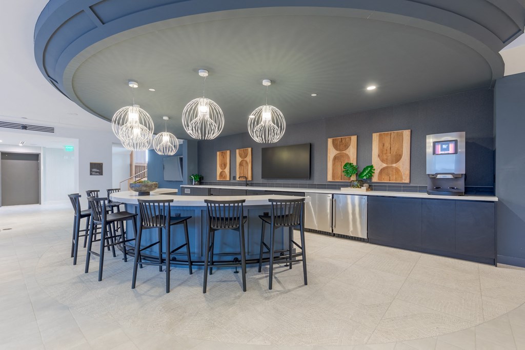 A modern kitchen with a curved island and bar stools.