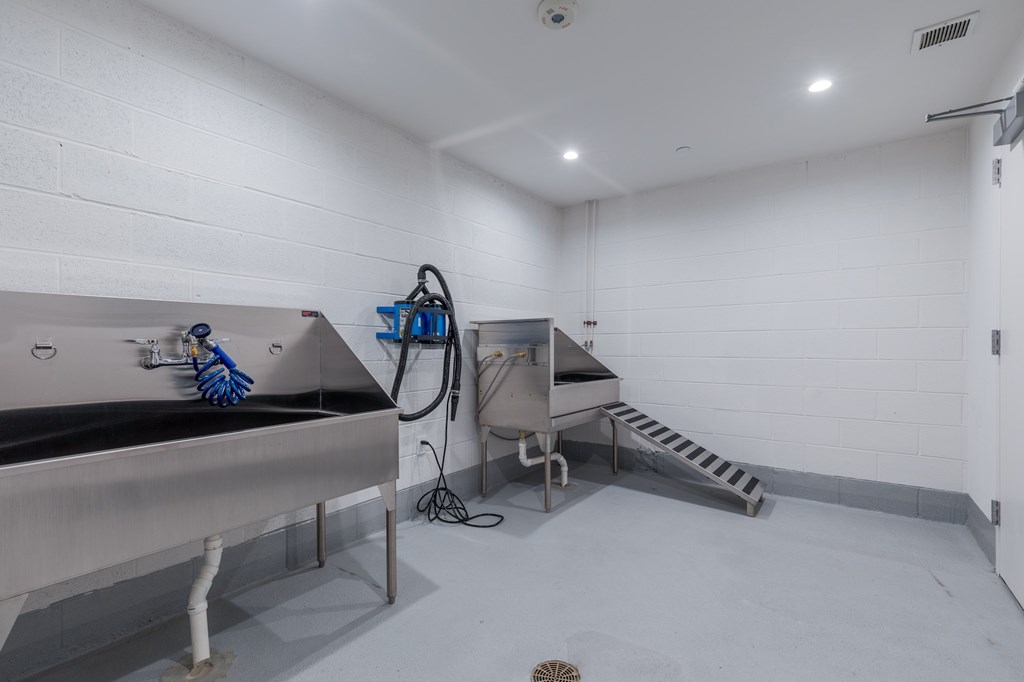 A cleaning cart with a blue mop and a vacuum cleaner is in a white room.