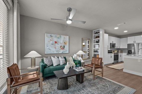 A living room with a green couch, a brown chair, and a painting on the wall.