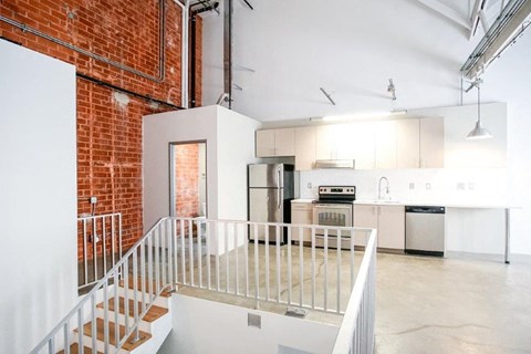 an empty loft with a kitchen and a staircase