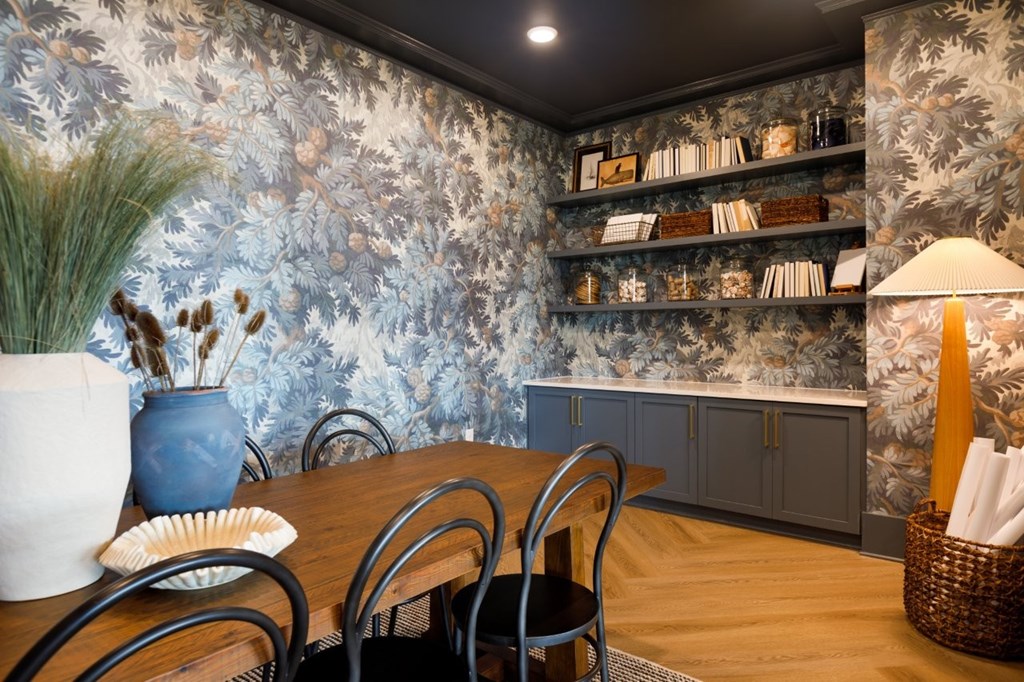 A dining room with a floral wallpaper and a wooden table.