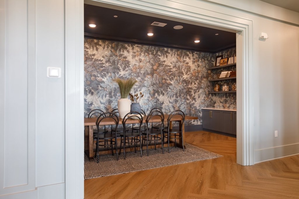 A room with a floral wallpaper and a table with chairs.