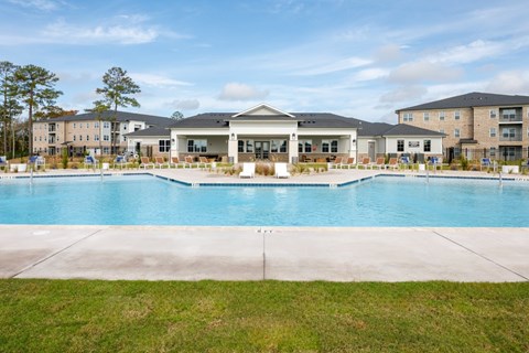 A large swimming pool in front of a building with a grassy area in the foreground.