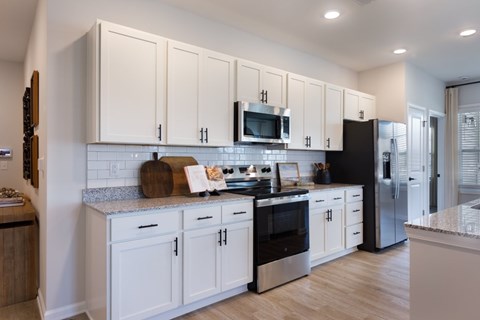 A kitchen with white cabinets and black appliances.