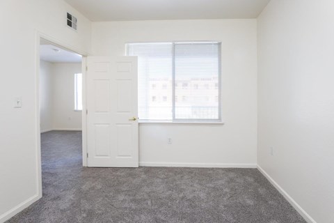 a bedroom with a door and a window and a carpeted floor