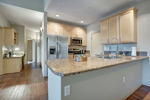 A kitchen with a granite countertop and stainless steel appliances.