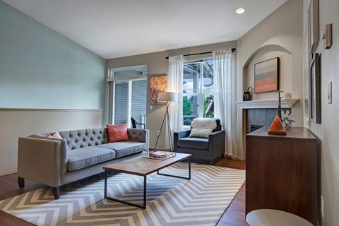 A grey couch with a red pillow sits in a living room.
